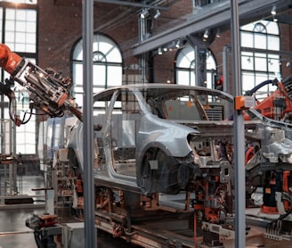 gray vehicle being fixed inside factory using robot machines