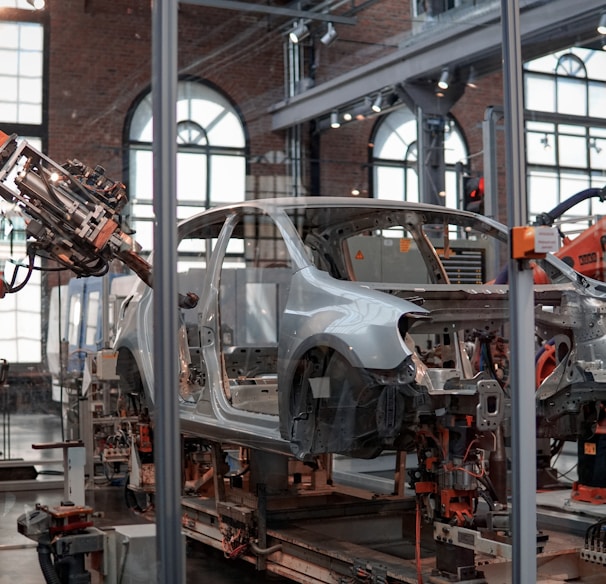 gray vehicle being fixed inside factory using robot machines