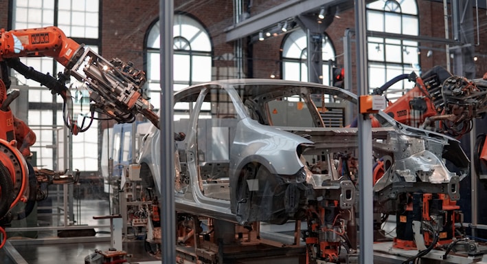 gray vehicle being fixed inside factory using robot machines