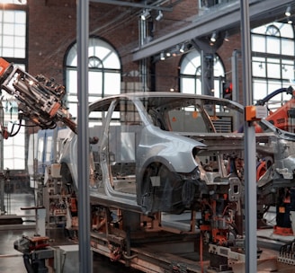 gray vehicle being fixed inside factory using robot machines