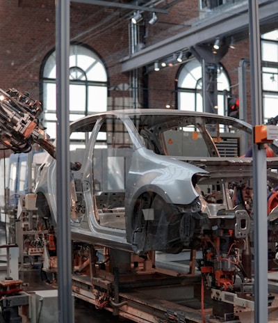 gray vehicle being fixed inside factory using robot machines