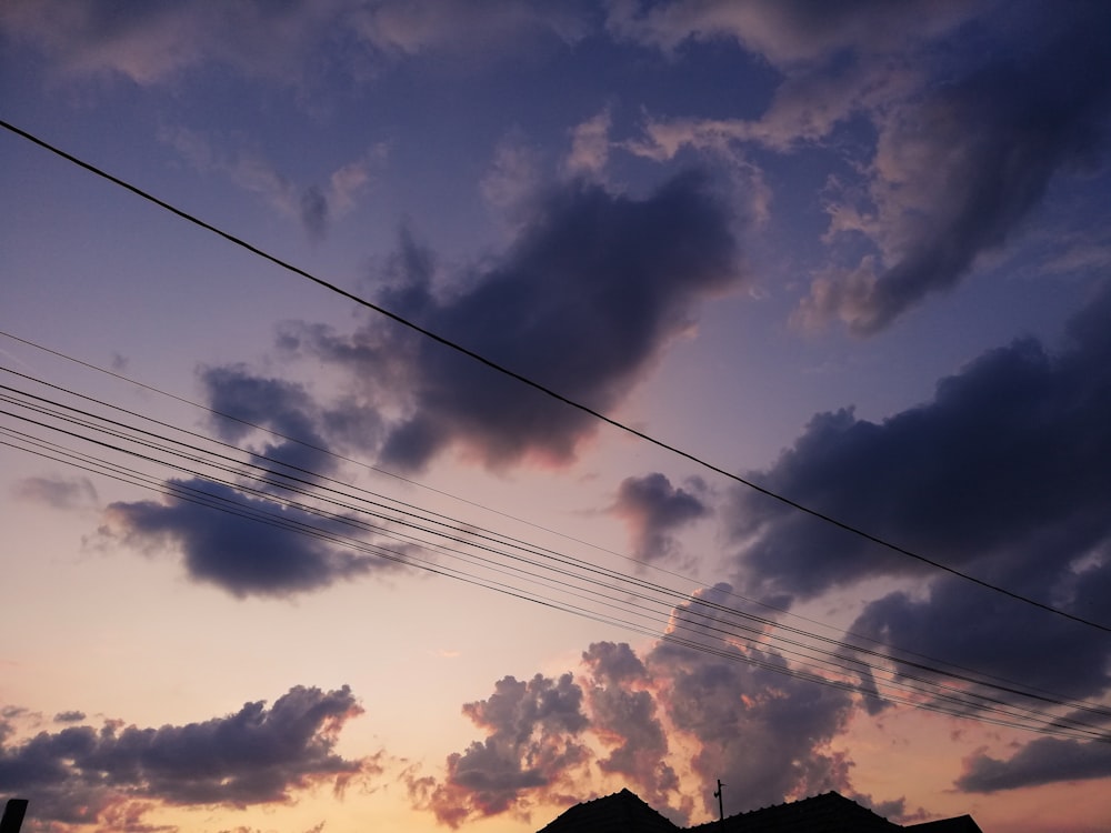 silhouette of cable wires under cloudy sky during golden hour