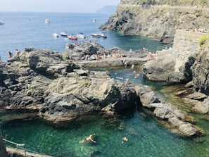 Tourists swimming in clear turquoise waters with the Toros mountains and natural coves in the background.