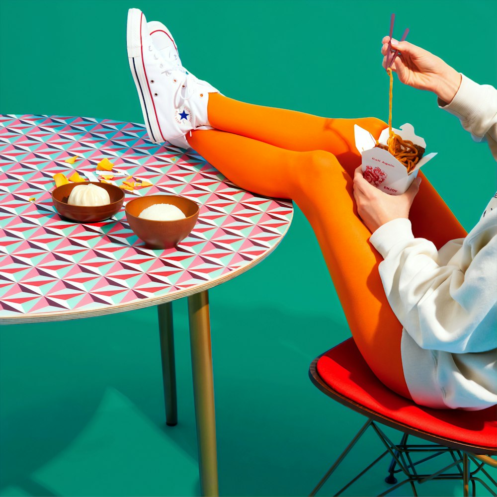 person siting while feet on table eating noodles