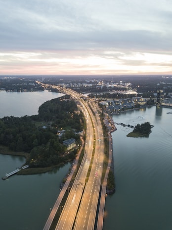 A sweeping aerial view of a newly constructed highway cutting through a lush African landscape at sunset.