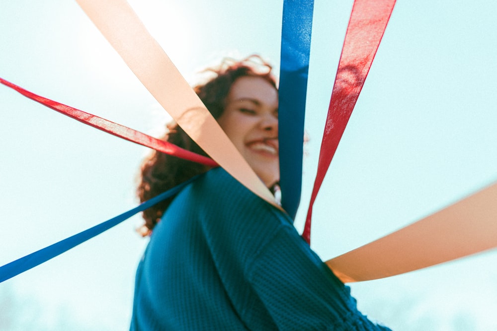 selective focus photography of smiling woman holding red, blue, and brown ribbons