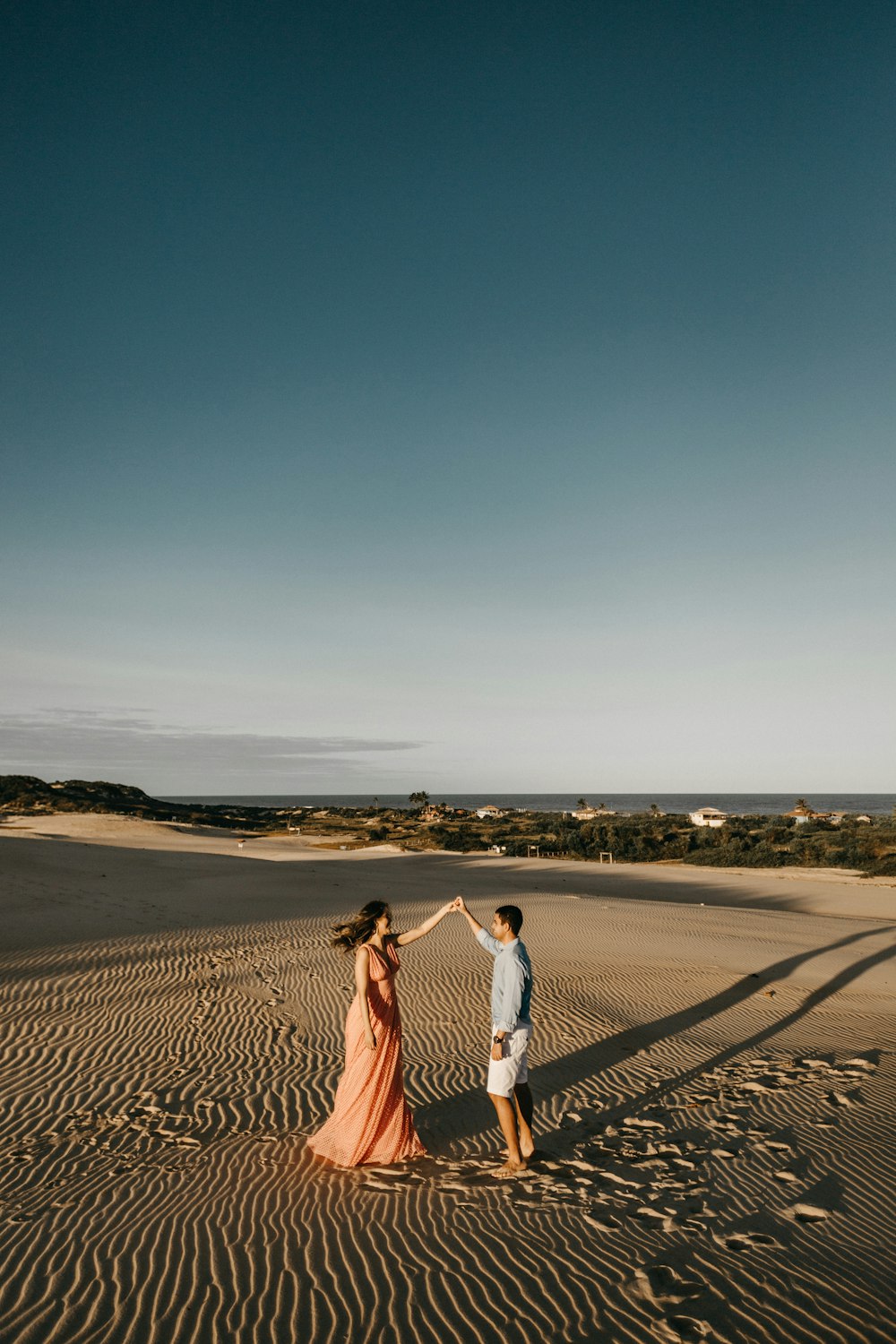 man and woman standing at sand dunes during daytime