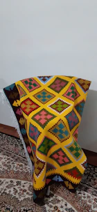 A vibrant Turkish scarf draped over a rustic wooden chair, showcasing bold geometric designs.