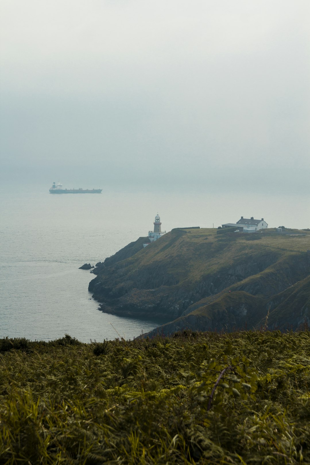 lighthouse near house on mountain island during day