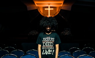 man wearing green t-shirt standing beside chairs inside church