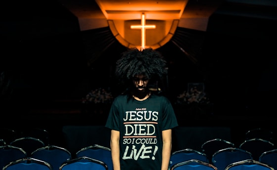 man wearing green t-shirt standing beside chairs inside church