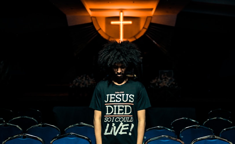 man wearing green t-shirt standing beside chairs inside church
