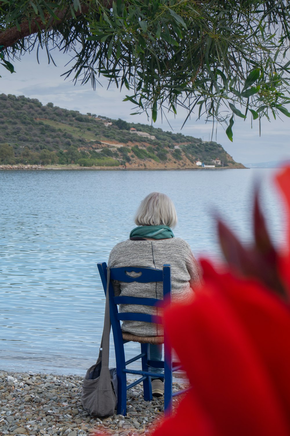 woman sits on chair looking the beach