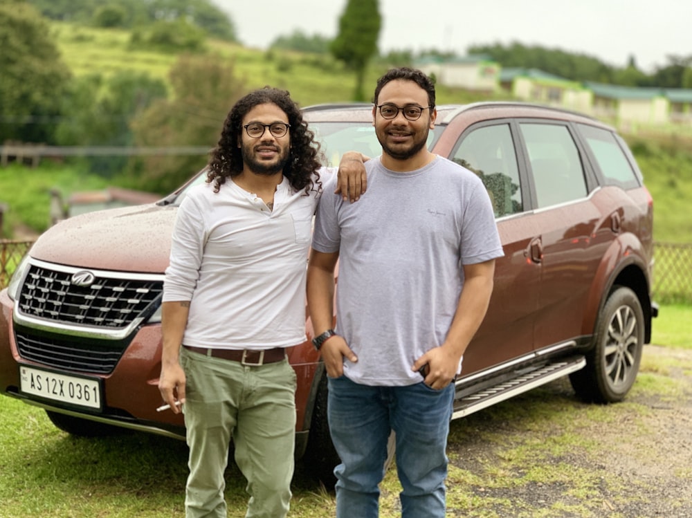 two men standing beside vehicle at daytime