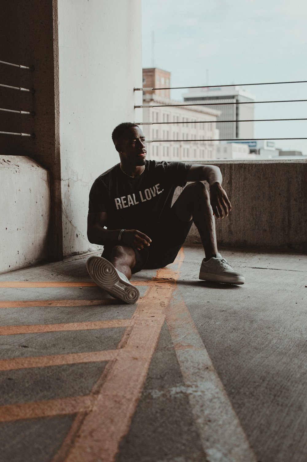 sitting man wearing Real Love shirt during daytime