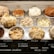 Various flavors of ice cream are displayed in a chilled dessert counter, each in its own metal tub with a different texture and color indicating the variety of flavors available. The names of the flavors such as tiramisu, cookies and cream, Italian nougat, and more are labeled on a board in front of the tubs.
