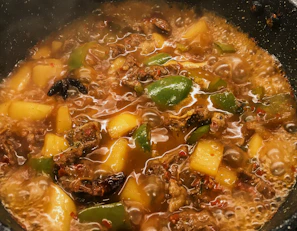 Top view of a non-stick pot simmering a hearty stew with steam rising