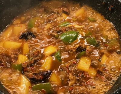 Close-up of a rustic wooden spoon stirring a simmering pot of hearty stew.