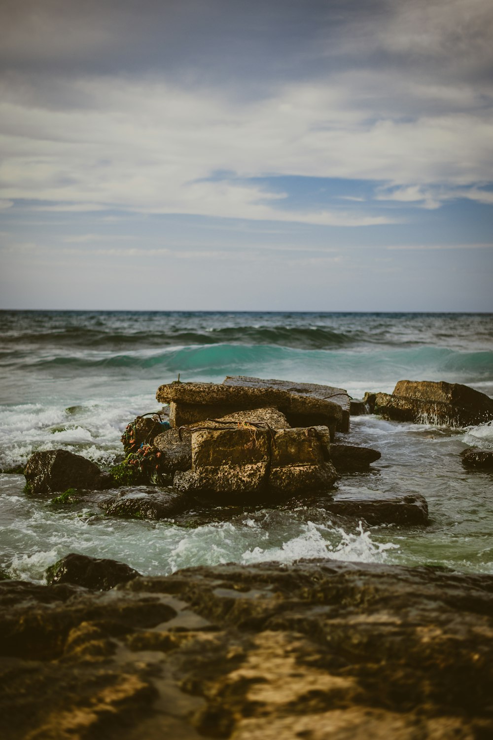 waves crashing on brown coastal rocks during daytime