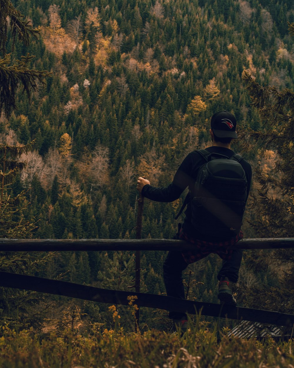 man sitting on brown fence during daytime