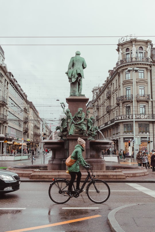 woman rides bike near statue in Zürich Switzerland