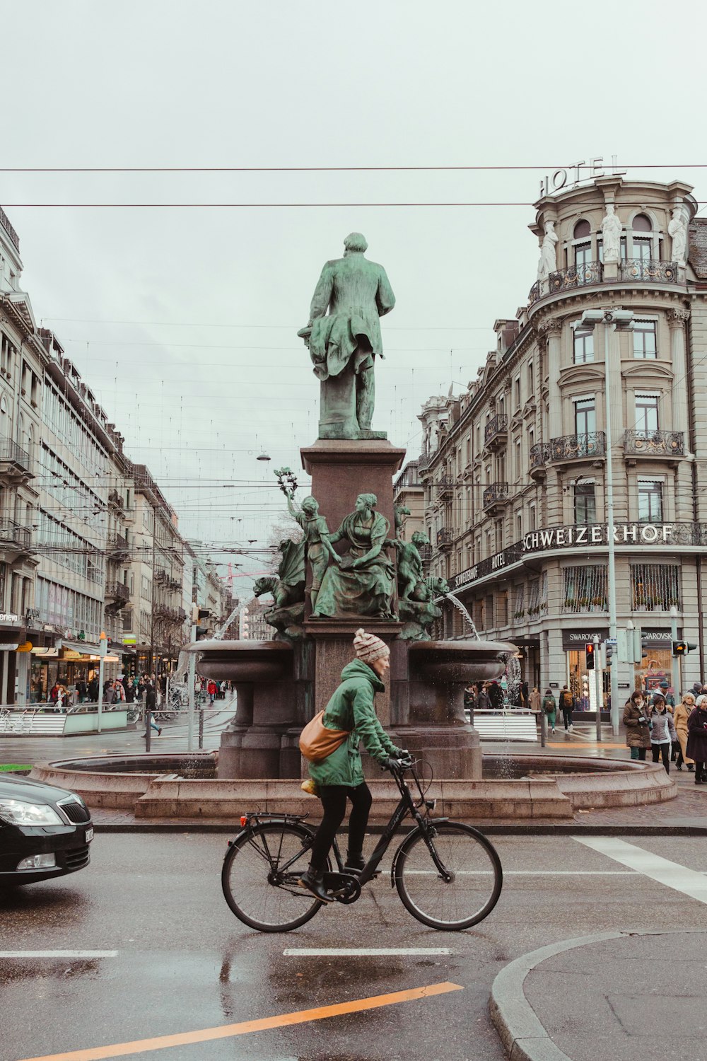 woman rides bike near statue