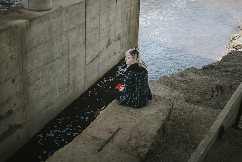 mulher sentada ao lado do rio