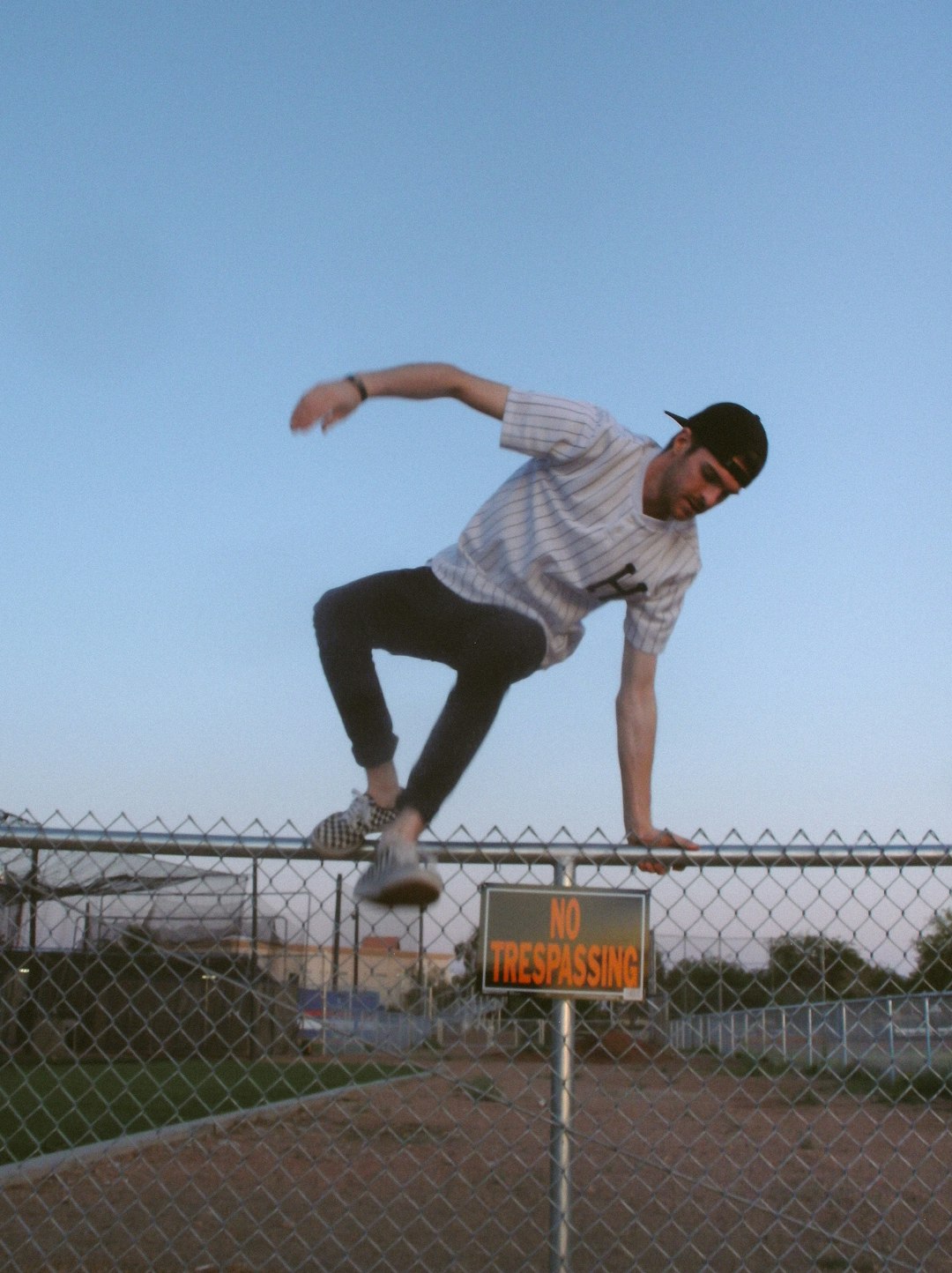 man jumping on stainless steel cyclone fence