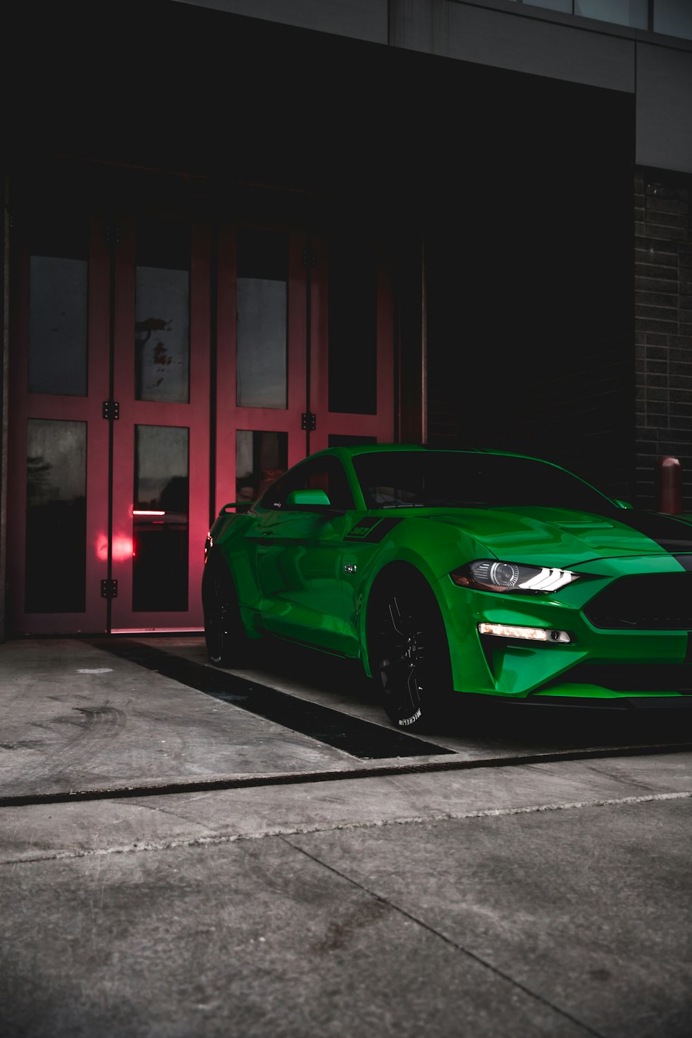 green coupe parked in front of garage doors