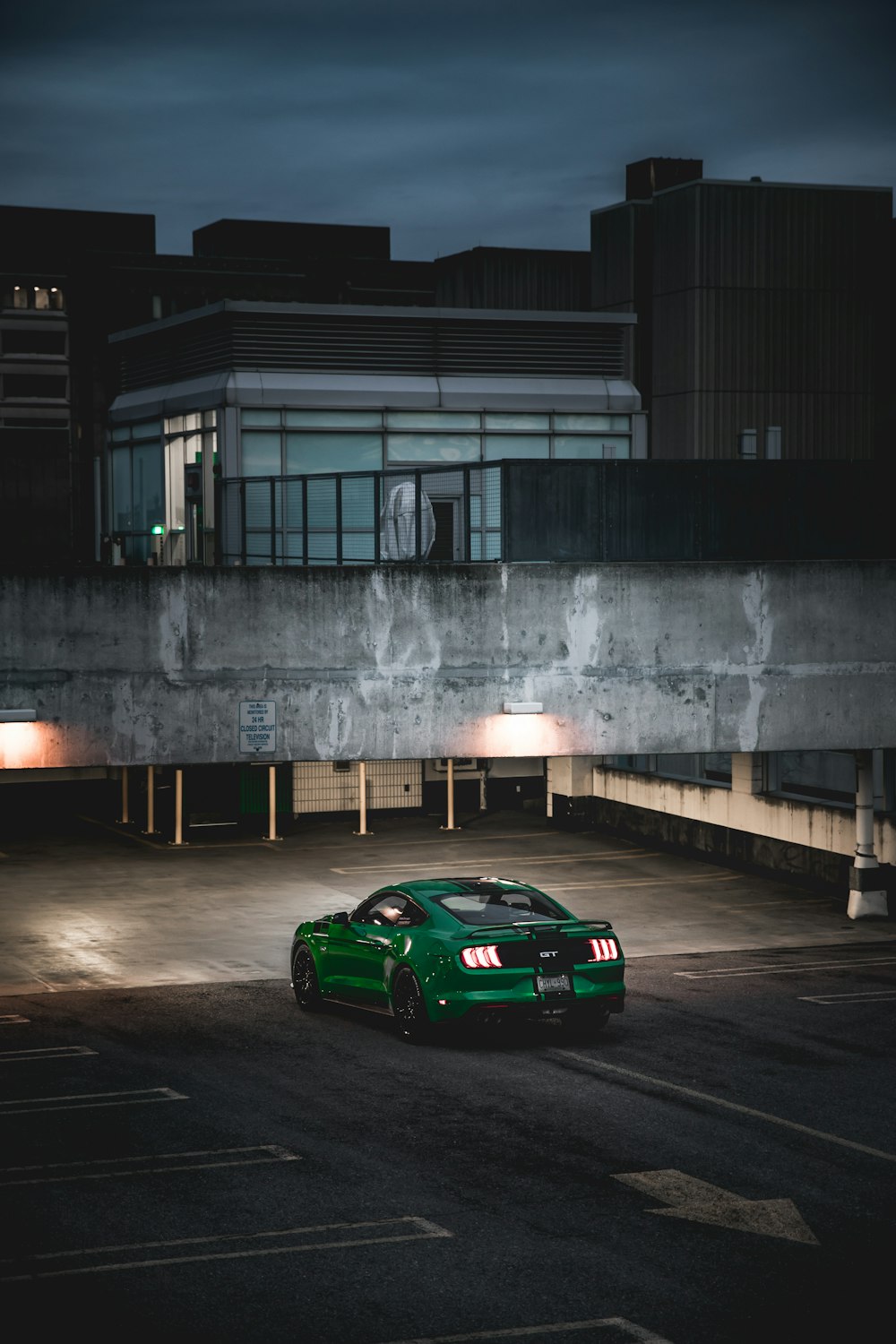 green coupe outside gray building