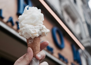 selective focus photography of person holding cup of ice cream