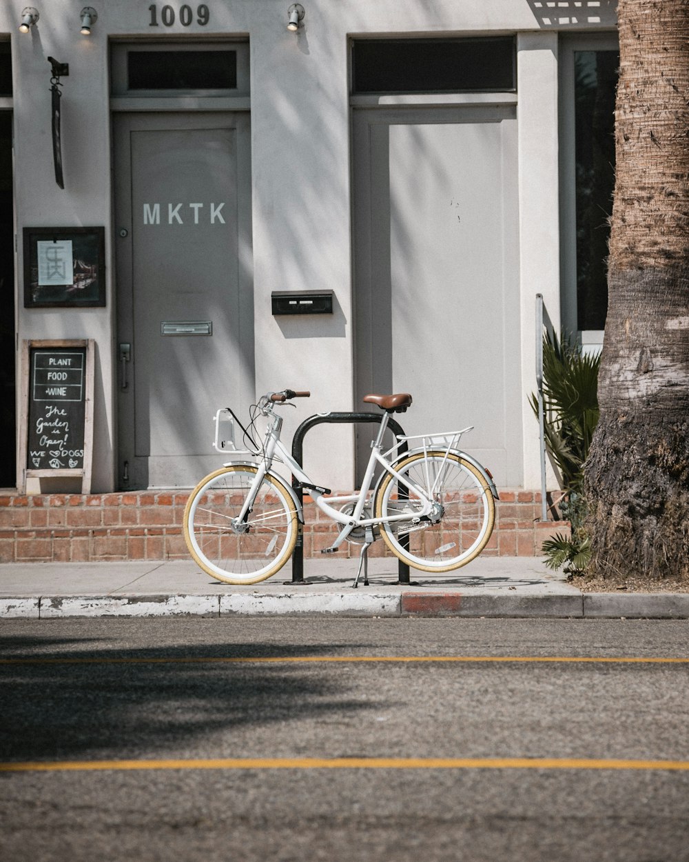 white commuter bike parks at paddock stand in front building number 1009