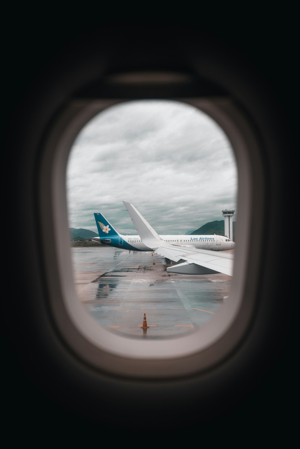 airplane window photo of white airplane under cloudy sky during daytime