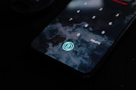 A smartphone screen displays a numeric keypad for password entry. There is a background resembling ocean waves and a circular fingerprint icon at the bottom.