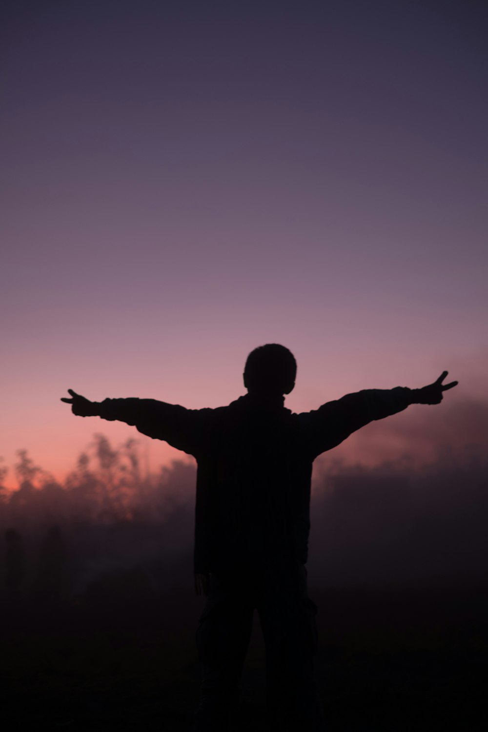 silhouette of person lifting arms