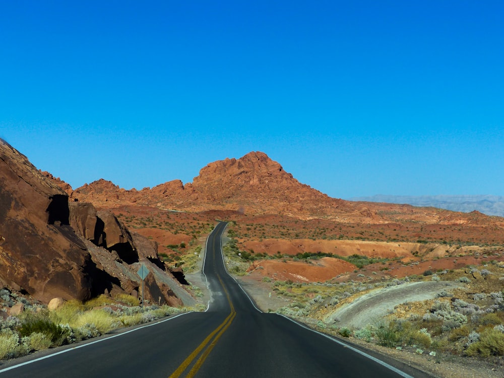 empty road near mountains under blue sky