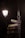 A street lamp illuminates a metal signpost at night. The signpost has several directional signs pointing to locations such as 'U.S. Club', 'Rani Jhansi Park', 'Mall Road', and 'Lift'. The background is dimly lit, with shadows and faint outlines of trees.