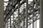 A complex metallic structure with numerous intersecting beams and rivets, creating a pattern of lines and angles. The beams display metalwork typical of industrial or infrastructure constructions.