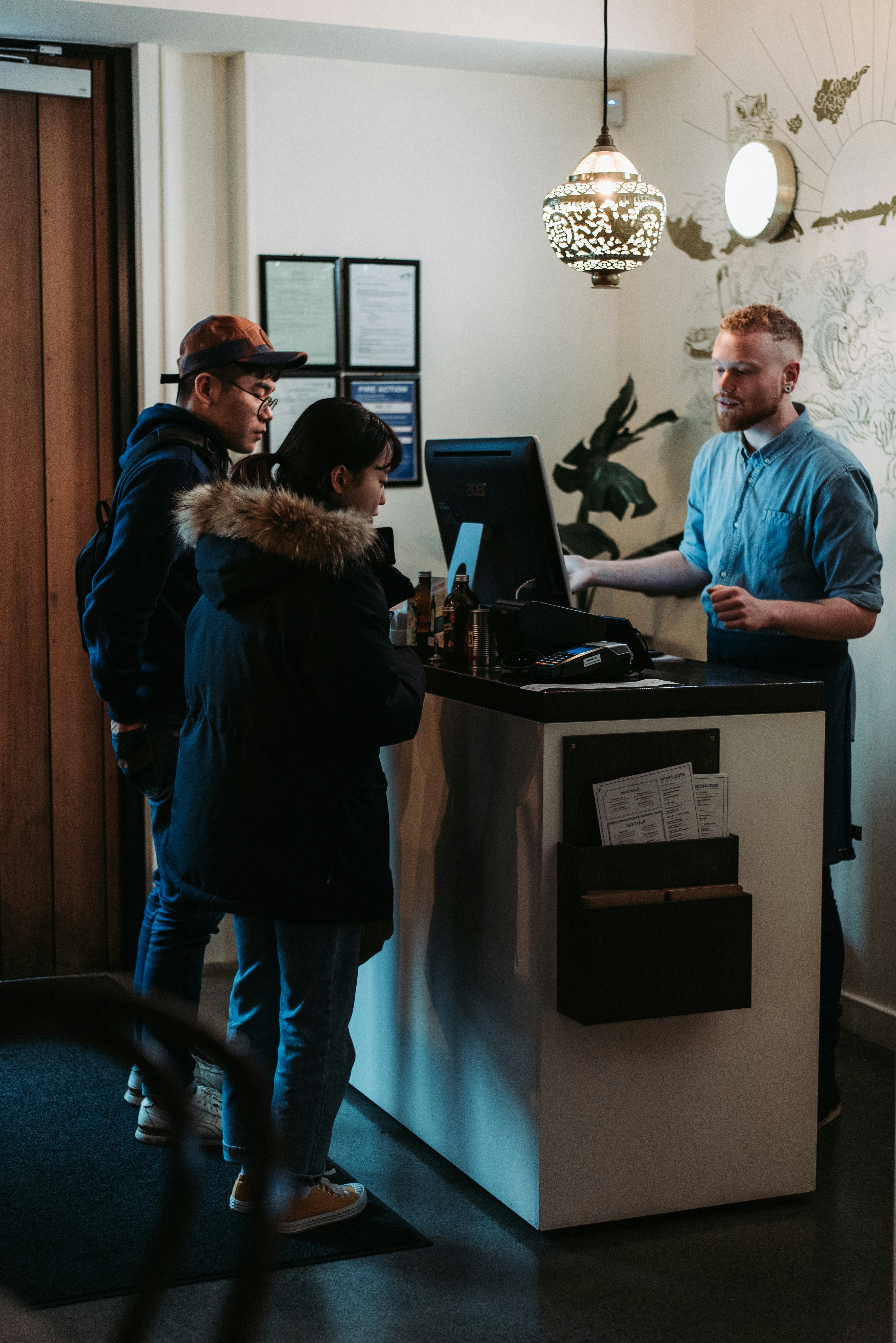 Man And Woman Standing In Front Of Man Behind Desk Photo Free