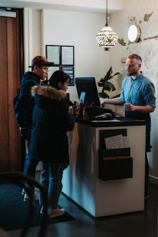 man and woman standing in front of man behind desk