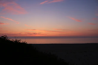 Sunset painting the sky in shades of pink and orange over a peaceful beach cove.