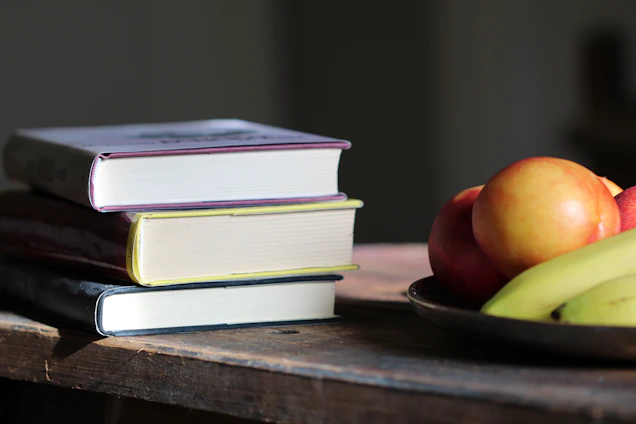 A stack of wellness books with soft natural light highlighting their calming covers on a wooden table.