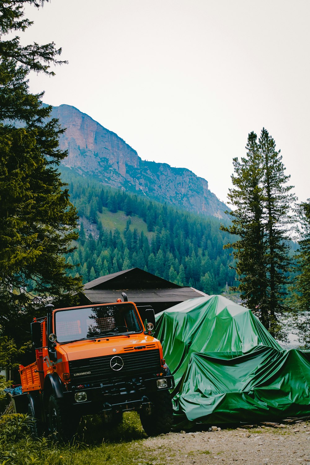 orange Mercedes-Benz truck near house viewing mountain