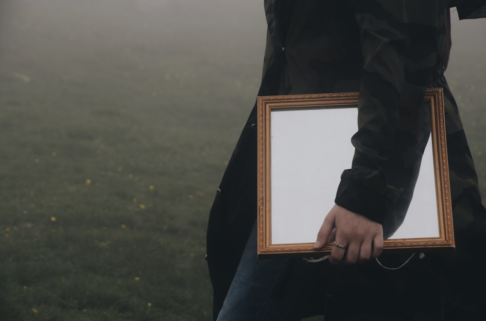 unknown person carrying rectangular mirror with brown frame