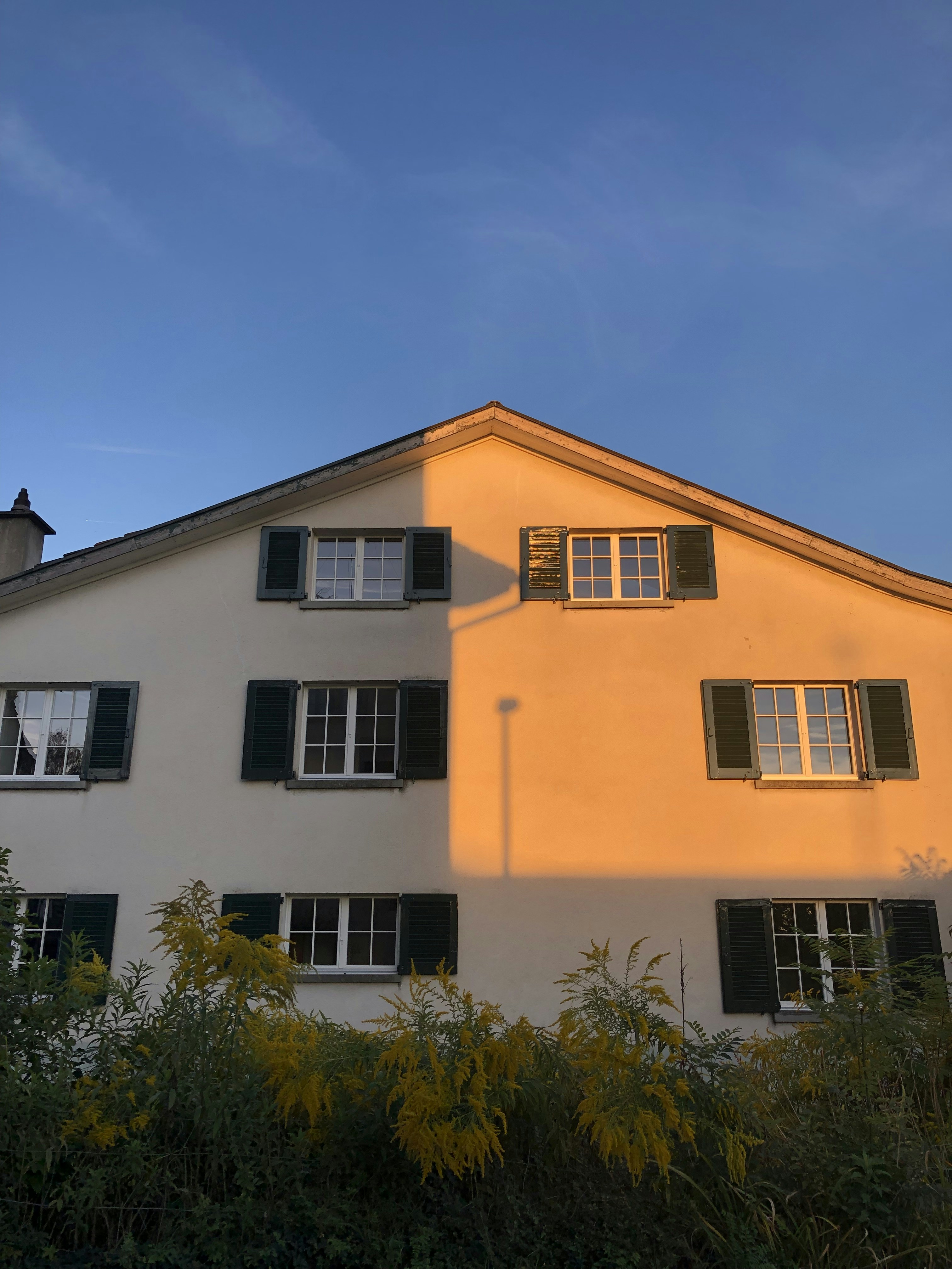 a white building with black shutters and windows