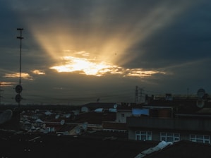 Beams of energy transmitting from space to a city skyline at dusk.