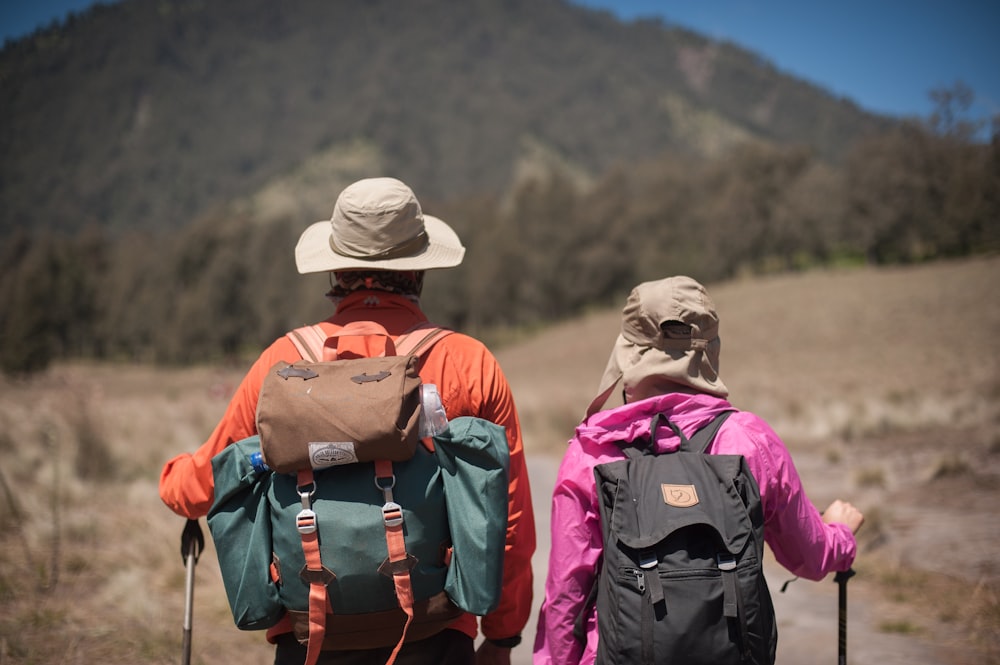 woman and man wearing hats and carrying backpack hiking
