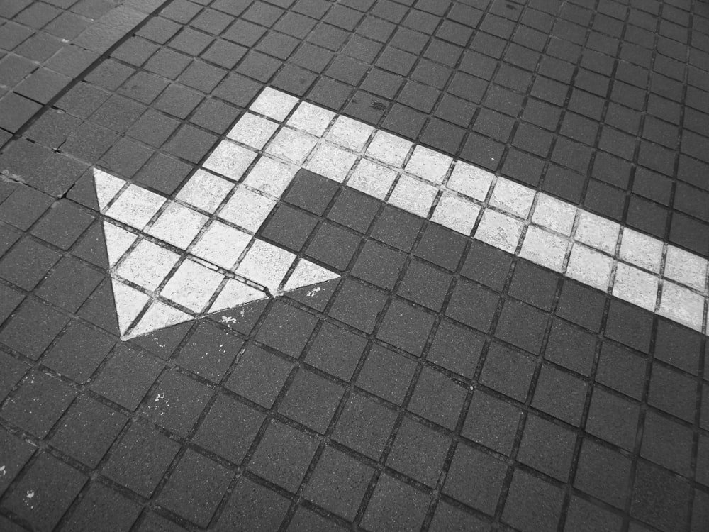 flecha blanca sobre pavimento enladrillado