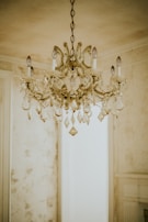 A delicate antique chandelier with crystal droplets hanging above a classic dining set.