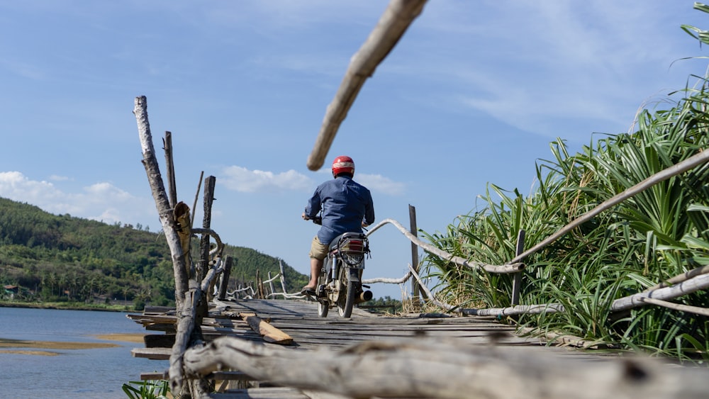 man riding motorcycle on wooden above water bridge during day